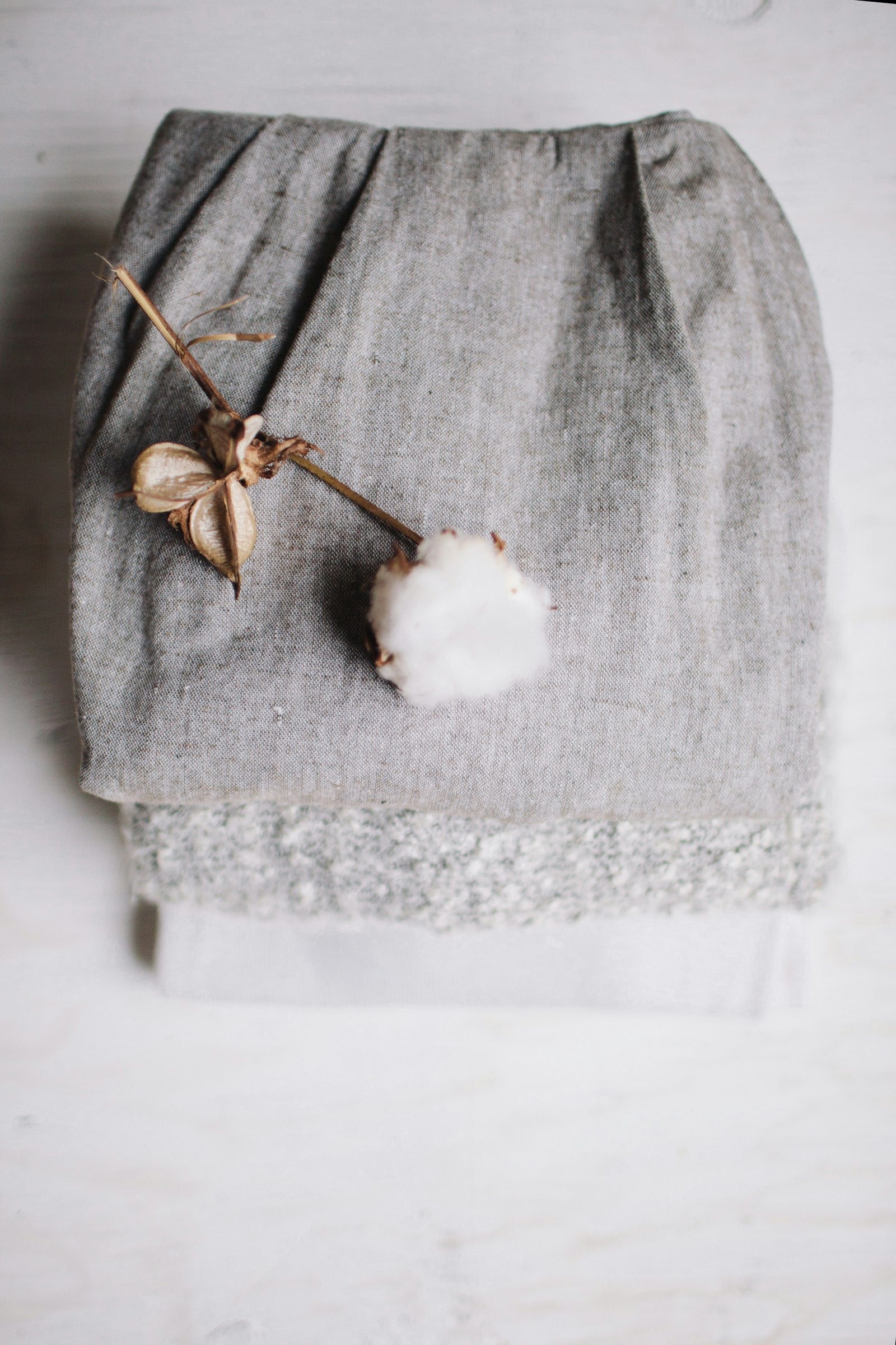 Soft natural cotton and linen textile folded with a cotton plant resting on top